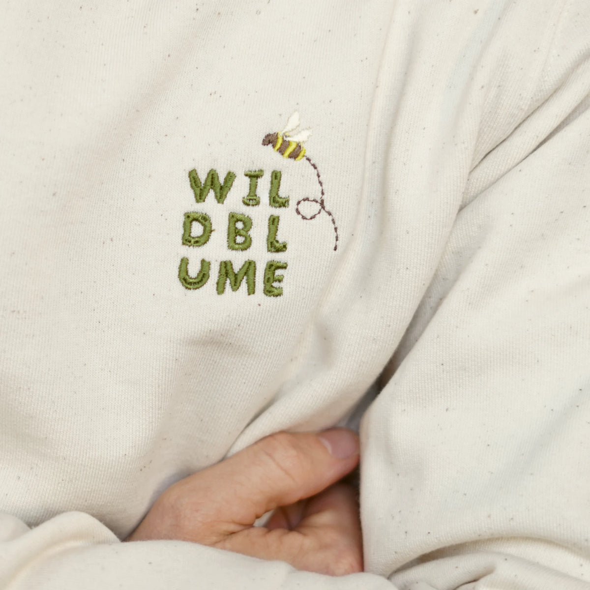 Sweater Robinga-Edition Auflage 2 – Makro der gestickten Brustmarke WILDBLUME mit Biene